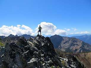 Man atop mountain peak against blue sky